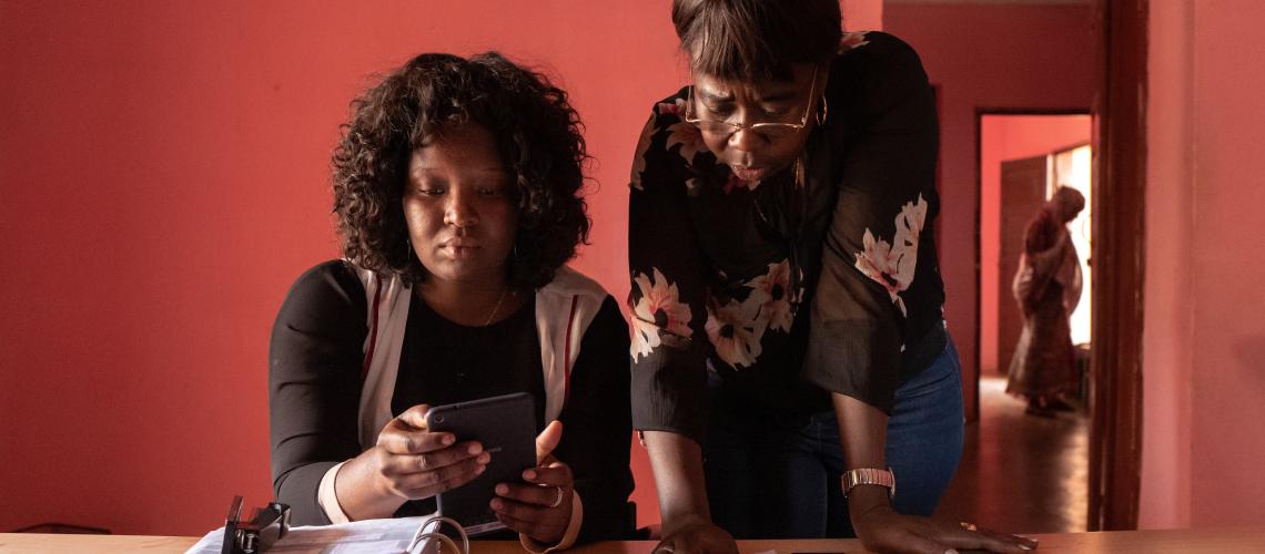 Two women at a working desk looking at documents and one woman in the background