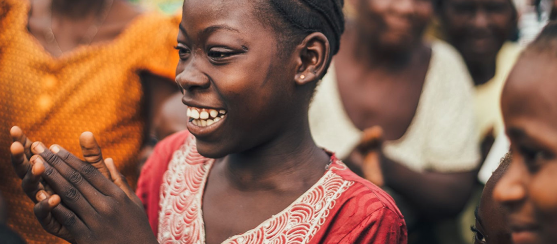 Woman in a crowd with her hands together and smiling