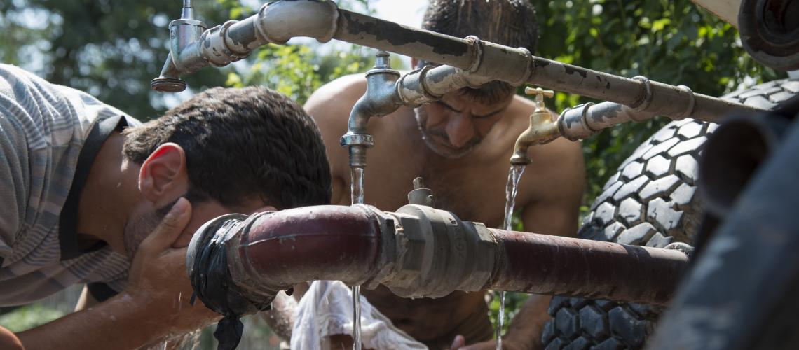 Men washing themselves by a water source