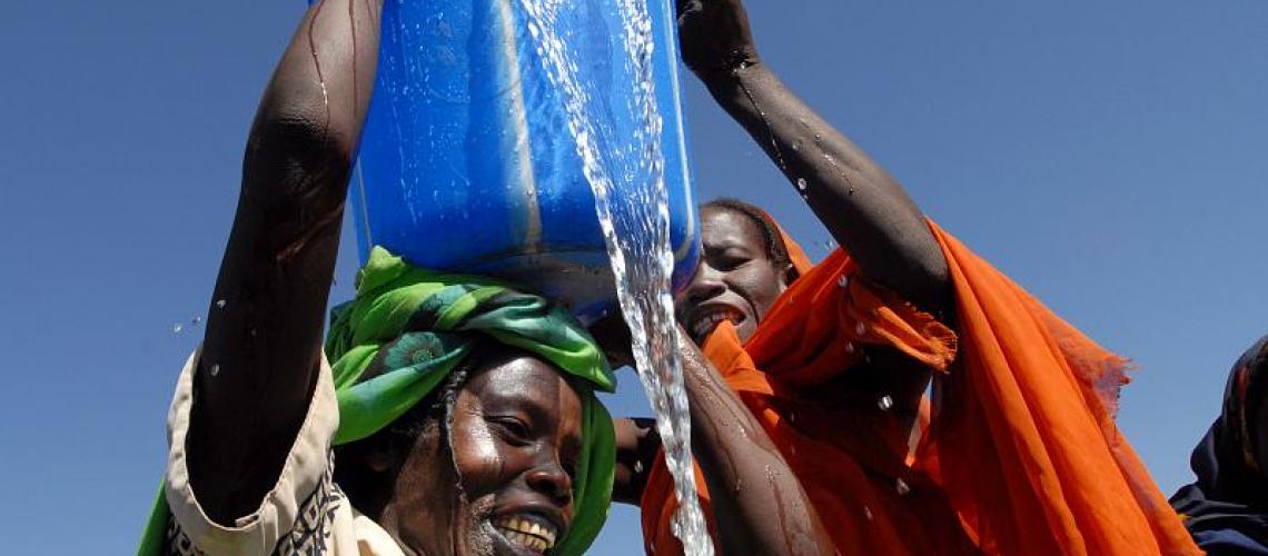 People raising large blue bucket spilling water