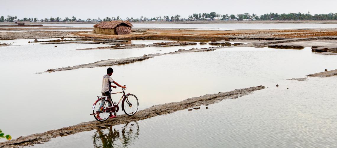 Man walking with bicycle in a flooded area