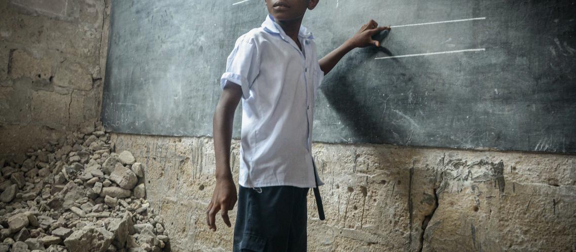 Young boy standing in front of blackboard