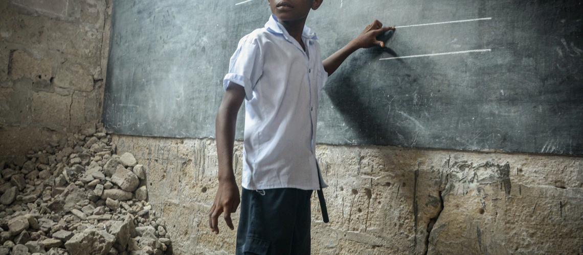 Young boy standing in front of blackboard