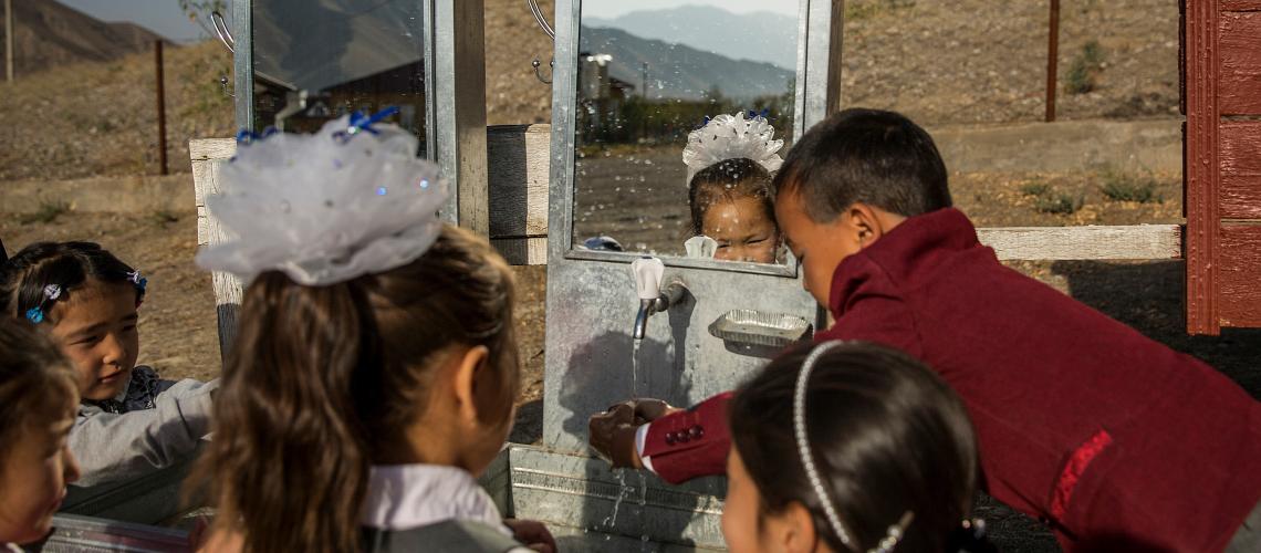 A group of young children washing their hands outside