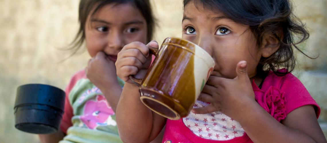 Two young girls drinking from cups