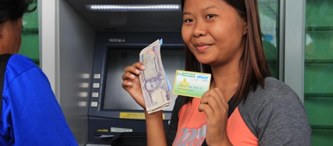 Lady near ATM with cash and card in hand