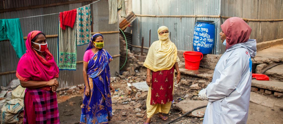 3 ladies with mask getting advised by PPE kit lady