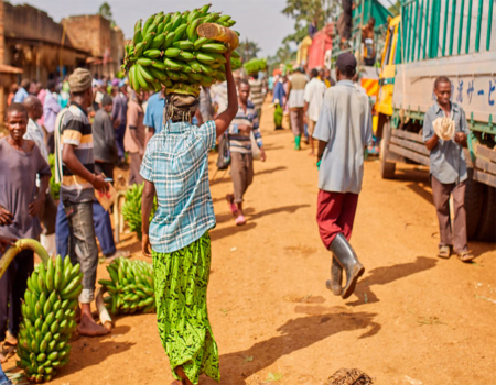 People carrying food down a path in a town