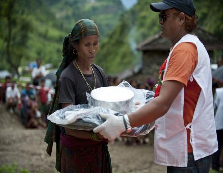 Red Cross worker handing package to woman