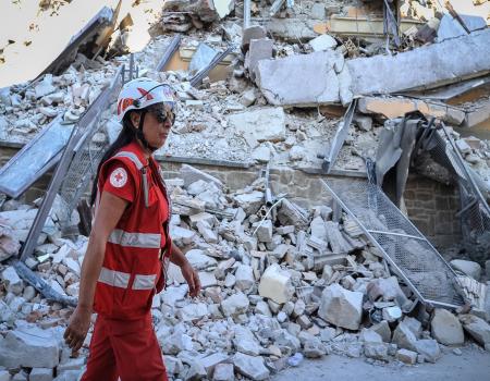 Humanitarian worker walking past demolished building