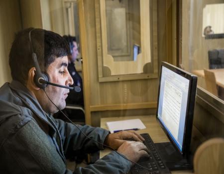 A man with headset sitting in front of a computer