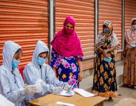 Women forming a line and two women sitting in front checking a list