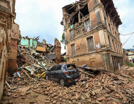 A destroyed car cloaked in debris from collapsed houses