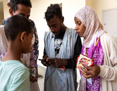 A group of young people looking at a mobile phone