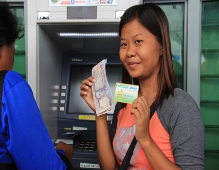 Lady near ATM with cash and card in hand