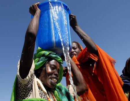 People raising large blue bucket spilling water